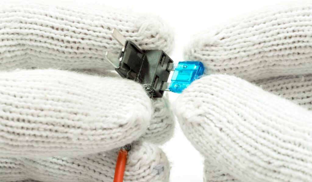 Man with knitted white gloves installing a mini fuse into a fuse tap