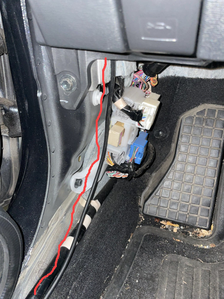 Rear dash cam cable dropping down from the fuse box into the driver's seat foot well.