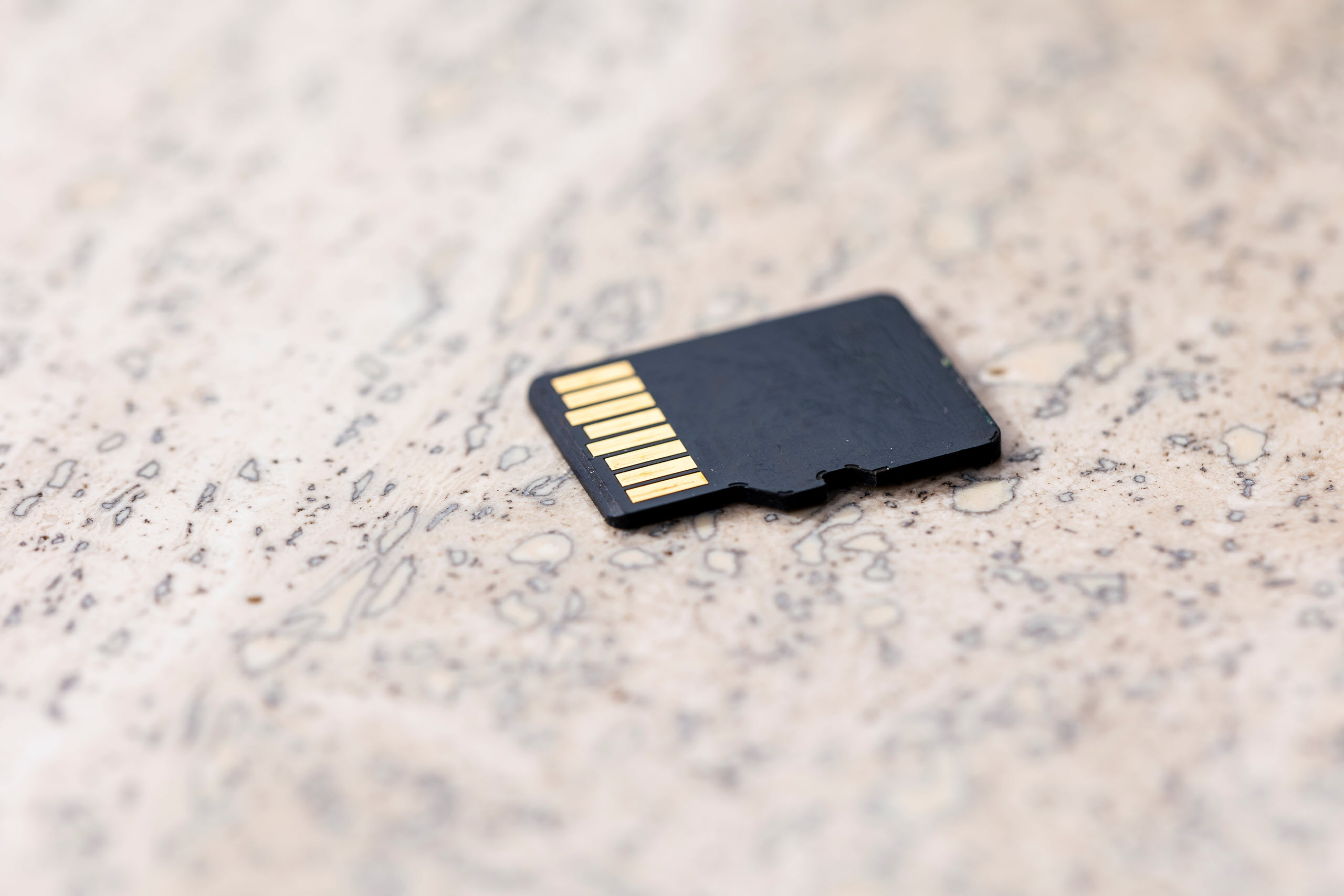 A black microSD card on a light brown textured back ground
